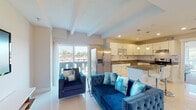Located in Memphis's 38104 zip code, this two-bedroom, one-bathroom unit at The Kay offers a thoughtfully designed single-floor layout with contemporary finishes throughout. The open-concept living area features light-toned tile flooring, exposed ceiling beams, and large sliding glass doors that flood the space with natural light while providing direct access to a private balcony with outdoor views. The living room comfortably accommodates seating and entertainment areas side by side.

The kitchen is well-appointed with white shaker cabinetry, granite countertops, a white subway tile backsplash, and stainless steel appliances including a refrigerator with ice maker, range, and dishwasher. A central island with bar seating and pendant lighting above adds both function and style.

Both bedrooms feature carpeted floors, ceiling fans, exposed beams, and walk-in closets. One bedroom includes sliding glass doors opening to a private balcony with tree-lined views. The shared bathroom is finished in a clean, modern aesthetic with a floating white vanity, large mirror, and a tiled shower-tub combination.
