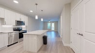 Located at 7350 Honore Ave in Sarasota, FL, this thoughtfully designed one-bedroom, one-bathroom residence offers a clean, contemporary aesthetic throughout. Light-toned wood-style flooring flows seamlessly across the entire unit, creating a cohesive and airy feel.

The open-concept kitchen and living area serves as the heart of the home. The kitchen is outfitted with white cabinetry extending to the ceiling, stainless steel appliances including a French door refrigerator, electric range, and microwave, as well as a granite-topped island with pendant lighting — ideal for both meal prep and casual dining.

The living area is bright and spacious, benefiting from a ceiling fan and direct access to a private balcony through a glass-paneled door, bringing in natural light and outdoor views of the surrounding greenery.

The generously sized bedroom features a ceiling fan, a large window with views of the outdoors, and access to two closets — including a walk-in closet equipped with wire shelving systems for ample organization.

The bathroom is clean and modern, featuring a granite-top vanity with under-mount sink, a glass-enclosed shower, and light wood-style tile flooring. A dedicated laundry area adds everyday convenience. The unit also includes recessed lighting throughout, completing this well-appointed Sarasota residence.