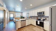 Located at 2580 Cahill Pond Vw in Colorado Springs, CO, this thoughtfully designed two-bedroom, three-bathroom residence offers a cohesive single-floor layout with modern finishes throughout. The open-concept kitchen is a standout feature, boasting white shaker cabinetry, granite countertops, a gray tile backsplash, and a full suite of stainless steel appliances including a refrigerator, electric range, microwave, and dishwasher. Wood-look flooring flows through the kitchen and living areas, lending warmth and continuity. The living room is bright and welcoming, with large windows fitted with blinds that allow natural light to filter in, alongside direct exterior access through a bold blue door. The primary bedroom offers a generous footprint with plush carpeting, a ceiling fan, and a dedicated en-suite bathroom featuring a dual-sink granite vanity and a tiled soaking tub with shower. A walk-in closet with wire shelving provides ample storage. The second bedroom also features carpeted flooring, a closet with a clothing rod, and convenient access to the adjacent kitchen area. The additional bathrooms maintain a consistent design with granite vanities and wood-look flooring. Recessed lighting throughout completes the clean, contemporary aesthetic of this Colorado Springs residence.