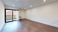 Located at 510 S Normandie Ave in Los Angeles' vibrant Koreatown neighborhood, this efficiently designed single-floor unit offers a clean, modern aesthetic throughout. Rich, warm-toned hardwood-style flooring runs continuously across the living spaces, complementing the crisp white walls and bright recessed lighting overhead.

The open living area is generously proportioned for its footprint, featuring a wall-mounted A/C unit and a sliding glass door that opens onto a private balcony, providing views of the surrounding neighborhood including palm trees and neighboring rooftops. A mirrored sliding closet in the living room adds both storage and a sense of expanded space. A floating shelf provides a functional accent detail.

The kitchen is efficiently laid out with granite-style countertops, white cabinetry, and a full suite of stainless steel appliances including a refrigerator, gas range, and dishwasher. A breakfast bar connects the kitchen to the living area, enhancing the open flow of the layout.

The bathroom features a vessel glass sink atop a marble-style vanity, white tiled shower/tub surround, and brushed nickel fixtures and grab bars. A connecting hallway ties the rooms together smoothly. Throughout, the unit maintains a clean, move-in-ready presentation with a bright, minimalist character well-suited to urban living.