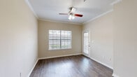 Located at 19800 Atascocita Shores Dr in Humble, TX, this single-floor residence offers a practical and comfortable layout designed to maximize every square foot. The living area features warm, wood-look hard flooring, neutral beige walls, crown molding, and a ceiling fan, creating a bright and inviting atmosphere with natural light filtering through the space.

The spacious primary bedroom is generously sized, finished with plush carpeting, a ceiling fan with light fixture, and a built-in desk or shelving nook beneath a large window — ideal for a workspace or reading area. The bedroom also provides direct access to a dedicated closet for ample storage.

The kitchen is efficiently designed, featuring light wood cabinetry, granite-style countertops, and white appliances including a refrigerator, electric range, and over-the-range microwave. Hard flooring carries through this functional space, making it easy to maintain.

A dedicated laundry area adds everyday convenience to the home. Throughout the residence, consistent neutral tones, white trim, and panel-style doors contribute to a clean, cohesive aesthetic. The thoughtful floor plan ensures a comfortable flow between all areas of this well-maintained Humble, TX home.