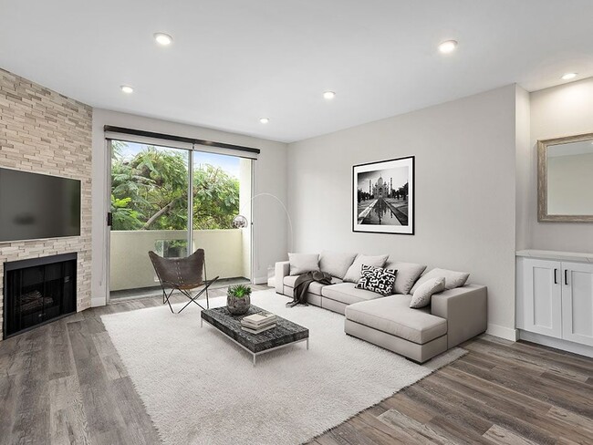 Hardwood floored living room with view of stone accent wall, fireplace, and private balcony. - Clarington Court