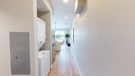 This thoughtfully designed residence in Auburn, WA offers a contemporary layout across a single floor, accommodating two bedrooms and two bathrooms. Light wood-tone flooring runs throughout the unit, providing a cohesive and clean aesthetic that complements the neutral gray-and-white color palette found in every room.

The open-concept kitchen and dining area serves as the heart of the home. The kitchen is equipped with stainless steel appliances, including a refrigerator, range, microwave, and dishwasher, set against light cabinetry with dark hardware and white countertops. A peninsula with pendant lighting provides seating and separates the kitchen from the dining and living areas. A large picture window in the living space fills the room with natural light while offering open views of the surrounding Auburn cityscape.

A central hallway connects the bedrooms, bathrooms, and a stacked in-unit washer and dryer. The primary bedroom features a cozy, understated design with light walls and wood-tone floors. The second bedroom includes a sliding closet and a narrow window for natural light. Both bathrooms are finished with light countertops, neutral walls, and clean, modern fixtures. Recessed lighting throughout the unit ensures consistent illumination across all spaces.