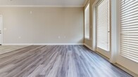 Located in Duncan, SC, this well-appointed 2-bedroom, 2-bathroom single-floor residence offers a thoughtfully designed layout with modern finishes throughout. The open-concept living, dining, and kitchen area forms the heart of the home, where gray luxury vinyl plank flooring flows seamlessly alongside neutral warm-toned walls and crisp white trim and baseboards. The kitchen stands out with rich dark espresso cabinetry, stainless steel appliances including a refrigerator, microwave, and range, granite countertops, a breakfast bar with pendant lighting, and tile flooring — all framed by crown molding for an elevated touch. The living area is bathed in natural light, courtesy of large French doors flanked by windows dressed with white horizontal blinds. The spacious primary bedroom features the same gray LVP flooring, an arched panel door, and direct hallway access to additional rooms. The bathrooms are finished with marble-style tile flooring, dark wood vanities, granite countertops, and classic white fixtures. A dedicated laundry room with tile flooring and built-in shelving adds everyday convenience. Throughout, consistent neutral tones, quality trim work, and cohesive finishes create a clean, move-in-ready atmosphere.