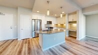 Located at 1774 Metro Avenue in Chula Vista, CA, this modern 2-bedroom, 2-bathroom apartment spans 980 square feet on a single floor. The open-concept kitchen and living area serves as the heart of the unit, featuring light wood-look flooring, white shaker cabinetry, a herringbone tile backsplash, stainless steel appliances, and a center island with a gray countertop and pendant lighting overhead. A built-in desk nook adds functional workspace. The living area extends to a private balcony through glass French doors, allowing ample natural light to fill the space. Both bedrooms are carpeted and generously windowed, offering views of the surrounding neighborhood. The primary bedroom measures 130 square feet and includes access to a dedicated closet. Both bathrooms are finished with light wood-look flooring, white vanity cabinetry, gray countertops, and large framed mirrors. A hallway connects the main living areas to the bedrooms and two closets, ensuring an efficient and logical layout. Neutral warm beige tones throughout the unit create a clean, contemporary aesthetic well-suited for comfortable everyday living in San Diego County.