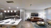 This stylish single-floor residence showcases a thoughtfully designed open-concept layout that seamlessly connects the kitchen and living areas. The kitchen is outfitted with rich dark cabinetry, stainless steel appliances, a classic subway tile backsplash, and a peninsula island with a white quartz countertop and an undermount sink — ideal for both meal preparation and casual dining. Pendant lighting above the island adds a warm, modern touch.

The transition into the living area is fluid and inviting, featuring light wood-style flooring that runs throughout and lends a sense of continuity across the space. The living room is warm and well-appointed, with neutral gray walls that serve as a versatile backdrop for contemporary décor. Recessed lighting throughout ensures the space remains well-lit and functional.

The overall ambiance strikes a balance between modern sophistication and everyday comfort, with clean lines, a neutral color palette, and coordinated design elements tying the space together. The open floor plan enhances the sense of spaciousness, making the home feel airy and connected — well-suited for both relaxed everyday living and entertaining guests.