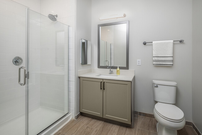 Bath with quartz countertop, tile backsplash, grey cabinetry, and hard surface flooring (representative imagery) - Avalon Princeton on Harrison