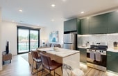 Dorothy is a thoughtfully designed 540-square-foot, one-bedroom, one-bathroom apartment spread across a single floor. The open-concept kitchen and living area serves as the heart of the unit, featuring light hardwood-style flooring, recessed lighting, and a sliding glass door that provides abundant natural light and outdoor access. The kitchen is outfitted with deep teal flat-front cabinetry, stainless steel appliances including a refrigerator and range, a chevron-patterned tile backsplash, and a marble-topped island with seating for two — ideal for casual dining or entertaining. The living area flows seamlessly from the kitchen, offering a comfortable, well-lit space. The primary bedroom spans 140 square feet and includes a large picture window with exterior views, a ceiling fan, and plush carpeting. A dedicated closet provides added storage. The bathroom features a striking design with floor-to-ceiling vertical teal tiles in a glass-enclosed walk-in shower, black fixtures, and a bold geometric black-and-white floor pattern. A separate closet rounds out the unit's functional layout, making Dorothy an efficient and stylish urban living space.