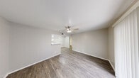 Located at 3010 East Nasa Parkway in Seabrook, Texas, this single-floor, two-bedroom, two-bathroom residence offers a well-organized and functional layout. The open living room is finished with durable wood-look flooring, a ceiling fan with integrated lighting, and a sliding glass door with vertical blinds that invites natural light and provides access to an outdoor area. A pass-through connects the living space to the galley-style kitchen, which features white cabinetry with brushed nickel hardware, light countertops, a stainless steel sink, and black appliances including a range, microwave, and refrigerator. The adjacent dining area shares the same cohesive flooring. A hallway leads to the two bedrooms, each equipped with ceiling fans and carpeted flooring. The primary bedroom offers a comfortable footprint with a window for natural light and access to a generous walk-in closet outfitted with built-in shelving and hanging rods. Three closets total provide ample storage throughout. Both bathrooms include a tub-shower combination with white tile surrounds. The overall palette of neutral tones and clean finishes creates a bright, move-in-ready atmosphere throughout the home.