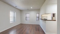 Located at 3220 Harrison St in Kansas City, MO, this single-floor, one-bedroom, one-bathroom unit offers a practical and well-appointed layout. The living room serves as the heart of the space, featuring rich, dark hardwood-style flooring, a textured ceiling, and multiple windows fitted with blinds that allow natural light to fill the room. A half-wall pass-through connects the living area to the galley-style kitchen, which is outfitted with dark espresso cabinetry, light granite-look countertops, a double stainless steel sink, and white appliances including a range, dishwasher, and refrigerator. The bedroom is carpeted for comfort, features two windows for natural light, and provides direct access to a utility room with in-unit washer hookup, as well as multiple closets for generous storage. The bathroom is clean and functional, offering a full tub-shower combination with a white surround, tile-look flooring, and a vanity with a well-lit mirror. A hallway connects the main living areas to the private spaces, contributing to an efficient and cohesive floor plan. Throughout the unit, neutral white walls and consistent finishes create a clean, move-in-ready ambiance.