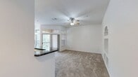 This well-appointed 1,110 square foot single-story home offers 3 bedrooms and 2 bathrooms with a thoughtful layout designed for comfortable living. The open-concept kitchen and living room serve as the heart of the home, featuring a peninsula with dark granite-style countertops, white shaker cabinets with brushed nickel hardware, a mosaic tile backsplash, and black appliances including a Whirlpool refrigerator and electric range. Track lighting illuminates the space, while a sliding glass door with transom windows above opens to an outdoor balcony, flooding the living area with natural light and tree-lined views. Built-in wall shelving adds a distinctive architectural touch to the living room. The bedrooms are carpeted and equipped with ceiling fans; the primary bedroom spans 160 square feet. Both bathrooms feature dark speckled countertops, white cabinetry, wood-look flooring, and tub/shower combinations. A dedicated laundry room houses a full-size Whirlpool washer and dryer. Three closets provide ample storage throughout the home, and a connecting hallway ties all spaces together efficiently.