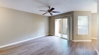 This single-floor, 2-bedroom, 1-bathroom residence in Florence, Kentucky offers a thoughtfully organized layout that maximizes its compact footprint. The living room features wood-style flooring, a ceiling fan with a brushed nickel fixture, and a sliding glass door that opens to an outdoor area, filling the space with natural light. Neutral gray walls throughout provide a clean, cohesive aesthetic.

Adjacent to the living room, the dining area is defined by a classic multi-bulb chandelier and a window dressed with blinds, adding warmth and character to the space. The galley-style kitchen is equipped with oak cabinetry, white countertops, black appliances including a refrigerator, electric range, and built-in microwave, and wood-style flooring that continues the consistent design theme.

The primary bedroom offers a comfortable footprint with carpeted flooring, a window for natural light, and access to a dedicated closet fitted with wire shelving and hanging rods. The second bedroom, also carpeted, maintains the same neutral tones. The full bathroom includes a tub-shower combination with a clean white surround. Two hallways connect the rooms efficiently, and white trim and baseboards provide a polished finish throughout.