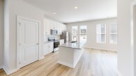 Located in Wendell, NC, this well-appointed three-story home offers four bedrooms and three bathrooms across a thoughtfully designed layout. The entry level features an attached garage with an automatic opener, concrete flooring, and direct interior access via a hallway with warm wood-look flooring and a staircase connecting the levels above.

The main living floor serves as the heart of the home, where an open-plan kitchen and living room combination creates a bright, airy atmosphere. The kitchen is outfitted with white shaker cabinetry, granite countertops, stainless steel appliances, and light hardwood-style flooring that continues into the living area. Multiple windows flood the space with natural light and offer views of the surrounding greenery.

The upper floor hosts the bedrooms, including a generously sized primary suite with a walk-in closet and a private en-suite bathroom featuring a dual-sink granite vanity and a separate shower. Additional bedrooms offer plush carpeting, ample closet space, and windows with tree-lined views. Shared bathrooms are finished with clean, neutral tones and modern fixtures.

Throughout the home, a consistent palette of soft neutral walls, clean white trim, and a mix of hardwood-style and carpet flooring creates a cohesive, move-in-ready aesthetic suited for comfortable everyday living.