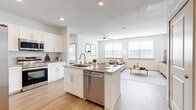 This well-appointed 2-bedroom, 2-bathroom residence offers a thoughtfully designed single-story layout that maximizes both comfort and functionality. Light-toned hardwood-style flooring flows seamlessly throughout the entire home, creating a cohesive and airy atmosphere.

The open-concept kitchen is a standout feature, showcasing white shaker cabinetry, granite countertops, and a central island with a built-in sink and dishwasher — ideal for both meal preparation and casual dining. Stainless steel appliances, including a side-by-side refrigerator and range, complete the modern kitchen setup.

The kitchen opens directly into the living room, which is bathed in natural light from multiple large windows fitted with horizontal blinds. A ceiling fan adds to the comfort of this welcoming gathering space.

The primary bedroom is a generously sized retreat, featuring large windows, a ceiling fan, and access to a spacious walk-in closet with wire shelving systems. The second bedroom is equally well-lit and comfortable. Both bathrooms are finished with granite-topped white vanities, wood-style flooring, and elegantly tiled tub-shower combinations featuring a marble-inspired surround. Three closets in total provide ample storage throughout the home.