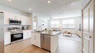 This well-appointed 2-bedroom, 2-bathroom residence offers a thoughtfully designed single-story layout that maximizes both comfort and functionality. Light-toned hardwood-style flooring flows seamlessly throughout the entire home, creating a cohesive and airy atmosphere.

The open-concept kitchen is a standout feature, showcasing white shaker cabinetry, granite countertops, and a central island with a built-in sink and dishwasher — ideal for both meal preparation and casual dining. Stainless steel appliances, including a side-by-side refrigerator and range, complete the modern kitchen setup.

The kitchen opens directly into the living room, which is bathed in natural light from multiple large windows fitted with horizontal blinds. A ceiling fan adds to the comfort of this welcoming gathering space.

The primary bedroom is a generously sized retreat, featuring large windows, a ceiling fan, and access to a spacious walk-in closet with wire shelving systems. The second bedroom is equally well-lit and comfortable. Both bathrooms are finished with granite-topped white vanities, wood-style flooring, and elegantly tiled tub-shower combinations featuring a marble-inspired surround. Three closets in total provide ample storage throughout the home.
