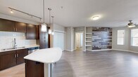 Located in Austin's vibrant 78704 zip code, this 2-bedroom, 2-bathroom residence offers a thoughtfully designed open-concept layout. The combined kitchen and living area forms the heart of the home, anchored by a striking wood-plank accent wall with built-in shelving. Light-toned hardwood-style flooring flows throughout the main living space, complementing the neutral palette and creating a bright, cohesive atmosphere. Large windows and a glass-panel door in the living room frame views of the Austin skyline, while a ceiling fan adds comfort overhead.

The kitchen is outfitted with rich dark-wood cabinetry, a white subway tile backsplash, light countertops, stainless steel appliances, and a peninsular island illuminated by stylish pendant lighting. Track lighting above the kitchen provides additional functionality.

Both bedrooms feature plush carpeting, ceiling fans, and windows that bring in natural light with city views. The primary bedroom is generously sized and includes dedicated closet space. The bathrooms are finished with dark-wood vanities, dual sinks, light countertops, and tile flooring, maintaining the consistent modern aesthetic found throughout the residence. A hallway connects the private areas of the home, completing this well-appointed urban layout.
