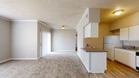 Located at 16401 Chenal Valley Dr in Little Rock, AR, this one-bedroom, two-bathroom residence offers a well-organized single-floor layout designed for comfortable everyday living. The open-concept living area features plush wall-to-wall carpeting, crown molding, a textured ceiling, and a large window that invites an abundance of natural light while offering outdoor views. A sliding door provides additional access and further enhances the brightness of the space. The kitchen is designed in a galley style with white cabinetry, granite-look countertops, a full suite of white appliances including an electric range and refrigerator, a dishwasher, and a stainless steel sink. Light wood-style flooring runs throughout the kitchen, adding warmth and contrast. The bedroom is generously proportioned, featuring soft carpeting, a natural light window, and a built-in desk with overhead cabinetry — a practical touch for a home office setup. A dedicated closet provides ample storage. Both bathrooms are well-appointed; one includes a soaking tub with a tiled shower surround, warm-toned accent walls, a vanity with white cabinetry, and wood-style flooring. The overall palette of neutral grays and warm tones throughout the unit creates a calm, cohesive ambiance.