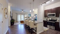 This single-floor residence offers a thoughtfully designed open-concept layout that seamlessly connects the kitchen, dining, and living areas. The kitchen is a standout feature, showcasing rich dark espresso cabinetry, granite countertops, a full suite of stainless steel appliances, a tile backsplash, and a spacious island with bar seating illuminated by elegant pendant lighting and track lighting overhead. Hardwood-style flooring flows throughout the main living areas, adding warmth and continuity to the space.

The living room is bright and inviting, finished with crown molding, a ceiling fan, and French doors that invite natural light and provide access to the outdoors. The two bedrooms are carpeted for comfort, each featuring large windows with outdoor views and ample room for furnishings.

The primary bathroom impresses with a wide double-sink vanity topped in granite, dark cabinetry with brushed nickel hardware, and a generous mirror. The second bathroom mirrors the same refined aesthetic with a single granite-topped vanity, dark cabinetry, and wood-style flooring. Together, the rooms create a cohesive, modern interior defined by quality finishes and a comfortable, livable atmosphere.