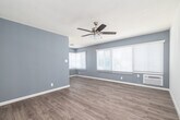 Located in the Hyde Park neighborhood of Los Angeles, this single-story 2-bedroom, 1-bathroom home offers a well-organized and functional layout. The living area features warm wood-look laminate flooring, cool-toned blue-gray walls, a textured ceiling, and a ceiling fan with integrated lighting. Multiple windows dressed with white horizontal blinds invite generous natural light throughout the space. Each bedroom continues the laminate flooring and neutral palette, with ceiling fans providing comfort. The primary bedroom offers a spacious closet with sliding doors and a wall-mounted air conditioning unit, while the second bedroom benefits from its own window and direct hallway access to the bathroom. The galley-style kitchen is efficiently designed with gray cabinetry, granite-look countertops, a stainless steel refrigerator, a double-basin sink, and tile flooring. A dedicated hallway connects the rooms cohesively, with a view into the kitchen's cabinet storage alcove. The full bathroom features a clean, all-white finish with a tub-shower combination, tiled surround, a single-sink vanity with under-cabinet storage, a mirror medicine cabinet, and a privacy window. The overall aesthetic is clean, bright, and move-in ready.