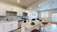 This thoughtfully designed 3-bedroom, 1-bathroom single-floor residence offers a cohesive contemporary aesthetic with clean lines and modern finishes throughout. The open-concept kitchen is a standout feature, boasting white shaker cabinetry, a grey subway tile backsplash, granite countertops, stainless steel appliances, and a peninsula with bar seating — ideal for casual dining and entertaining. The kitchen flows seamlessly into the living room, which features wood-look flooring, large windows with horizontal blinds that invite natural light, and a private exterior door. The bedrooms are carpeted for comfort and include ceiling fans, ample natural light from well-placed windows, and soft neutral wall tones that create a calm, restful atmosphere. The primary bedroom offers a cozy yet functional layout. The shared full bathroom is finished with large-format marble-style tile in the tub/shower surround, a granite vanity top, white cabinetry, and wood-look flooring, maintaining a consistent design language with the rest of the home. A connecting hallway ties all rooms together efficiently. The overall ambiance is modern, light, and welcoming, with a neutral palette and quality finishes that suit a variety of lifestyles.