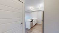 This well-designed 1-bedroom, 1-bathroom unit offers a thoughtful layout with modern finishes throughout. The open-concept kitchen and living area creates a bright, cohesive space anchored by light-toned luxury vinyl plank flooring. The kitchen is equipped with stainless steel appliances — including a refrigerator, electric range, over-the-range microwave, and dishwasher — complemented by crisp white cabinetry, white quartz countertops, a double-basin sink, and track lighting overhead. The living area is airy and functional, featuring a wall-mounted mini-split HVAC unit for year-round climate control. A sliding glass door leads to a private balcony with views of mature trees and green surroundings, allowing abundant natural light to fill the room. The bedroom is a comfortable size, complete with a sliding-door closet offering built-in shelving. The full bathroom features a white vanity with ample drawer storage, a large mirror with overhead lighting, and a shower-tub combination. A dedicated laundry room houses a full-sized front-loading washer and dryer. The unit's neutral grey palette and clean, contemporary aesthetic create a cohesive and functional living environment.