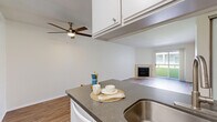 Located on Dickens Street in the heart of Sherman Oaks, Los Angeles, this 2-bedroom, 2-bathroom residence offers a thoughtfully designed single-floor layout. The open-concept kitchen and living area form the core of the space, where wood-style flooring flows throughout. The kitchen is equipped with white cabinetry, dark countertops, a gas range, built-in microwave, and a peninsula with a stainless steel sink that overlooks the living room — ideal for both cooking and entertaining. A ceiling fan with a light fixture keeps the living area comfortable, while a tile-surround fireplace serves as a focal point. Sliding glass doors open to a private balcony with courtyard views, allowing natural light to fill the room. The bedrooms are carpeted for comfort and feature mirrored sliding closet doors that enhance the sense of space. The primary bedroom includes a dedicated closet with shelving. Neutral tones and clean white walls create a bright, airy ambiance throughout. The building exterior features a multi-story stucco facade with balconies overlooking a landscaped courtyard, offering a classic Southern California residential setting.