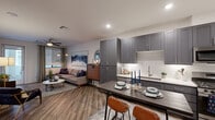 Located in Scottsdale, AZ, this thoughtfully designed one-bedroom, one-bathroom residence offers a modern and cohesive aesthetic throughout. The open-concept kitchen and living area serves as the heart of the home, where sleek gray shaker cabinetry, stainless steel appliances, white quartz countertops, and a textured geometric tile backsplash create a polished, contemporary kitchen. A central dining bar provides casual seating, while wood-look plank flooring flows seamlessly into the living area, which features a ceiling fan and windows that invite natural light. The living room offers a comfortable, well-proportioned layout with room for a sectional sofa and media setup. The bedroom is carpeted for comfort, equipped with a ceiling fan, and features a striking sliding barn door that opens to a generously sized walk-in closet complete with built-in shelving and dual hanging rods for ample storage. The bathroom is finished with gray shaker vanity cabinetry, a white quartz countertop, a framed mirror, brushed nickel fixtures, and a full soaking tub with shower. Recessed lighting throughout the residence enhances the clean, modern ambiance, making this Scottsdale home a well-appointed and functional living space.
