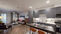 Located in Scottsdale, AZ, this thoughtfully designed one-bedroom, one-bathroom residence offers a modern and cohesive aesthetic throughout. The open-concept kitchen and living area serves as the heart of the home, where sleek gray shaker cabinetry, stainless steel appliances, white quartz countertops, and a textured geometric tile backsplash create a polished, contemporary kitchen. A central dining bar provides casual seating, while wood-look plank flooring flows seamlessly into the living area, which features a ceiling fan and windows that invite natural light. The living room offers a comfortable, well-proportioned layout with room for a sectional sofa and media setup. The bedroom is carpeted for comfort, equipped with a ceiling fan, and features a striking sliding barn door that opens to a generously sized walk-in closet complete with built-in shelving and dual hanging rods for ample storage. The bathroom is finished with gray shaker vanity cabinetry, a white quartz countertop, a framed mirror, brushed nickel fixtures, and a full soaking tub with shower. Recessed lighting throughout the residence enhances the clean, modern ambiance, making this Scottsdale home a well-appointed and functional living space.