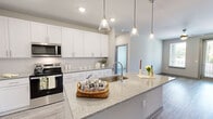 This well-designed 2-bedroom, 2-bathroom single-floor residence in Suwanee, GA offers a thoughtfully planned open-concept layout with contemporary finishes throughout. The kitchen serves as the centerpiece of the home, showcasing crisp white shaker cabinets, stainless steel appliances, a subway tile backsplash, and a generous granite-topped island with an undermount sink and pendant lighting — ideal for both everyday cooking and casual entertaining. The kitchen flows seamlessly into the living area, which benefits from natural light and access toward an exterior door.

Wood-look plank flooring runs throughout the home, providing a cohesive, modern aesthetic. The primary bedroom offers a comfortable footprint with a ceiling fan, a large window with outdoor views, and direct access to a well-appointed bathroom featuring a soaking tub/shower combo. A dedicated walk-in closet with wire shelving and hanging rods provides excellent storage. The second bedroom is bright and clean, with neutral tones and ample space. Two closets across the home ensure practical storage solutions. The overall ambiance is clean, modern, and move-in ready, making this Suwanee residence a functional and attractive living space.