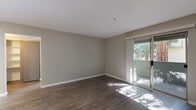 Located on N Milpitas Blvd in Milpitas, California, this single-floor unit offers a thoughtfully designed open-concept layout with contemporary finishes throughout. The main living area is bright and spacious, featuring dark hardwood-style flooring, neutral gray walls, and clean white baseboards. A sliding glass door floods the room with natural light and provides direct access to an outdoor patio, where views of lush greenery create a pleasant connection to the outdoors.

The kitchen is well-appointed with gray shaker-style cabinetry, white quartz countertops, and a classic subway tile backsplash. Stainless steel appliances — including a refrigerator, electric range, and over-the-range microwave — offer a sleek, functional workspace. A pass-through counter connects the kitchen to the living area, enhancing the open feel of the space.

The bedroom is generously sized with large windows dressed in horizontal blinds, allowing natural light while maintaining privacy. It includes a walk-in closet with built-in shelving, providing ample storage. The bathroom features gray vanity cabinetry, a full tub-shower combination with brushed nickel fixtures, and wood-look tile flooring, completing the space with a clean, modern aesthetic.