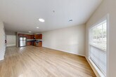 Located at Charley's Place in Bay Shore, NY, this single-floor, one-bedroom, one-bathroom unit offers a well-organized layout designed for comfortable everyday living. The open-concept main area seamlessly combines the living room, dining space, and kitchen into one bright, cohesive zone. Light hardwood-style flooring runs throughout the living areas, complemented by neutral beige walls and recessed lighting that create a clean, modern aesthetic. Multiple windows fitted with blinds allow ample natural light to fill the space. The kitchen is well-appointed with warm-toned wood cabinetry, dark countertops, and a full suite of stainless steel appliances including a gas range, refrigerator, and dishwasher. The living and dining area benefits from a dedicated entryway with additional window access, enhancing both light and ventilation. The generously sized primary bedroom features soft wall-to-wall carpeting, two large windows overlooking greenery, and a ceiling light fixture, providing a comfortable and quiet retreat. Two closets offer practical storage throughout the unit. The bathroom features tile flooring in a neutral stone pattern with clean white fixtures. A utility room rounds out the layout, adding functional storage and service space.