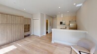 Located in the East Falls neighborhood of Philadelphia, this thoughtfully designed single-floor residence at 3624 N Conrad St offers a clean, modern aesthetic throughout. Light hardwood flooring flows seamlessly across the open-concept living area, creating a warm and cohesive foundation for the space.

The kitchen is a standout feature, showcasing bold navy-blue lower cabinetry paired with light wood upper cabinets, a classic white subway tile backsplash, stainless steel appliances, and a peninsula with a white quartz countertop and matte black faucet — ideal for both cooking and casual dining.

The living area is open and airy, benefiting from recessed lighting and a natural connection to the kitchen. Built-in shelving and cabinetry in a warm wood tone provide ample storage and a refined architectural detail.

The bedroom is bright and comfortable, with multiple windows fitted with roller shades that invite natural light and offer views of the surrounding greenery. A wall-mounted ductless mini-split system ensures efficient climate control year-round.

The bathroom is sleek and contemporary, featuring large-format dark tile flooring, crisp white walls, and a frameless glass-enclosed walk-in shower with a built-in niche — a polished finish to this well-appointed space.