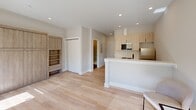 Located in the East Falls neighborhood of Philadelphia, this thoughtfully designed single-floor residence at 3624 N Conrad St offers a clean, modern aesthetic throughout. Light hardwood flooring flows seamlessly across the open-concept living area, creating a warm and cohesive foundation for the space.

The kitchen is a standout feature, showcasing bold navy-blue lower cabinetry paired with light wood upper cabinets, a classic white subway tile backsplash, stainless steel appliances, and a peninsula with a white quartz countertop and matte black faucet — ideal for both cooking and casual dining.

The living area is open and airy, benefiting from recessed lighting and a natural connection to the kitchen. Built-in shelving and cabinetry in a warm wood tone provide ample storage and a refined architectural detail.

The bedroom is bright and comfortable, with multiple windows fitted with roller shades that invite natural light and offer views of the surrounding greenery. A wall-mounted ductless mini-split system ensures efficient climate control year-round.

The bathroom is sleek and contemporary, featuring large-format dark tile flooring, crisp white walls, and a frameless glass-enclosed walk-in shower with a built-in niche — a polished finish to this well-appointed space.