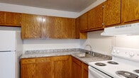 This two-story residence in Taylor, Michigan offers a practical and well-organized layout across two levels. The main floor features a kitchen equipped with warm oak cabinetry, granite-patterned countertops, a stainless steel sink, a white electric range, and a full-size refrigerator. Wood-look flooring runs through the kitchen, adding durability to a high-traffic area. The living area on this level is carpeted and receives natural light through a window fitted with vertical blinds, and includes a wall-mounted air conditioning unit and baseboard heating for year-round climate control. A carpeted staircase connects the two floors. The full bathroom includes a white vanity with a large mirror, wood-look flooring, and a tub-shower combination. The three bedrooms are carpeted and finished in neutral tones, with each room featuring baseboard heating. Two of the bedrooms include windows with vertical blinds and wall-mounted air conditioning units, while one bedroom benefits from two windows, allowing for additional natural light and outdoor views. The overall design is clean and straightforward, providing a comfortable and functional living environment.