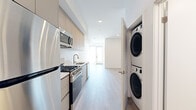 Located at 3001 Beverly Blvd in Los Angeles, this modern 2-bedroom, 1-bathroom unit offers a clean, contemporary design throughout its single-floor layout. Light wood-tone flooring runs seamlessly across every room, complementing the crisp white walls and recessed lighting that create a bright, airy ambiance.

The galley-style kitchen is well-appointed with stainless steel appliances including a gas range, over-the-range microwave, and full-size refrigerator, paired with flat-front cabinetry in a warm wood finish and light countertops. A stacked in-unit washer and dryer is conveniently tucked just off the kitchen.

The open living area provides a comfortable, flexible space bathed in natural light. Both bedrooms are generously proportioned with recessed lighting and closet storage, while the primary bedroom features a walk-in closet. One bedroom boasts a large window with expansive views of the Los Angeles skyline and surrounding cityscape, filling the room with abundant natural light.

The bathroom is finished in a clean, all-white palette with a full tub-shower combination, a vanity with storage, and light wood-tone flooring that echoes the rest of the unit. The overall design is minimal and modern, offering a move-in-ready living space in the heart of Los Angeles.