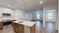 Located at 373 E Main St in Branford, Connecticut, this single-floor unit showcases a clean, contemporary design with high-quality finishes throughout. The open-concept layout connects the kitchen and living area seamlessly, creating a bright and functional living space. Recessed lighting and natural light from multiple windows contribute to an airy, welcoming atmosphere, complemented by durable wood-tone flooring that runs consistently throughout the main areas.

The kitchen serves as a central focal point, featuring a large island with a white quartz countertop, an undermount sink, and warm wood-toned lower cabinetry paired with crisp white upper cabinets. Stainless steel appliances, including a refrigerator, range, microwave, and dishwasher, complete the space. The living area is generously sized with a wall-mounted mini-split HVAC unit providing efficient climate control.

The bedrooms offer comfortable proportions with ample closet space and additional mini-split units. The bathrooms are finished with large-format light marble-style tile flooring, warm wood vanities topped with white countertops, and sleek fixtures. One bathroom includes a glass-enclosed tub and shower combination. The overall aesthetic is modern, clean, and move-in ready.