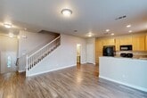 Located at 3339 Marlee Way in Rocklin, California, this two-story home offers a well-organized layout across two floors. The main level features a bright, open-concept living room and kitchen combination with warm wood-look flooring throughout. The kitchen is equipped with light maple cabinetry, granite countertops, a peninsula island, and black appliances including a gas range and refrigerator, all illuminated by recessed lighting. A downstairs bathroom and access to the attached garage with its high ceilings and concrete flooring round out the ground floor. A white-railed staircase leads to the upper level, which is carpeted throughout and houses all four bedrooms and additional bathrooms. The spacious primary bedroom features dual windows that invite natural light and views of the surrounding greenery, and connects to a private en-suite bathroom complete with a soaking tub, dual-sink vanity, and hardwood-style flooring. Each bedroom includes closet space, with several walk-in closets featuring built-in shelving and hanging rods. The home includes five closets total, providing ample storage throughout. Neutral tones and clean finishes give the entire home a move-in-ready feel.