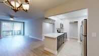 Located at 101 Steuben Dr. in Albany, NY, this well-appointed single-floor residence offers one bedroom, two bathrooms, and a thoughtfully designed layout spanning a comfortable footprint. The open-concept living, dining, and kitchen area serves as the heart of the home. The kitchen is a standout, featuring crisp white shaker cabinetry, striking marble-look countertops, a central peninsula, and stainless steel appliances including a refrigerator, range, microwave, and dishwasher — all illuminated by recessed lighting. The dining area flows naturally from the kitchen and is accented by an elegant chandelier and light hardwood-style flooring that continues throughout the main living spaces. The living room is bright and airy, with large sliding glass doors dressed in vertical blinds that invite natural light and provide views of the surrounding greenery. The generously sized primary bedroom features soft carpeting, a ceiling fan, a dedicated closet, and a window overlooking the outdoors. Both bathrooms are clean and functional, with one featuring a glass-enclosed walk-in shower. A dedicated closet adds to the practical storage throughout. Baseboard heating is present throughout, and neutral tones give the entire residence a move-in-ready, versatile feel.