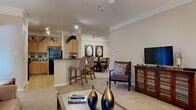 This 2-bedroom, 2-bathroom residence at 325 Spears Creek Church Rd in Elgin, SC offers a thoughtfully designed single-floor layout that maximizes comfort and functionality. The open-concept living, dining, and kitchen area serves as the heart of the home, with crown molding, recessed and track lighting, and neutral tones creating a warm, inviting ambiance. The living room features plush carpet, a ceiling fan, and a glass door that fills the space with natural light. The kitchen is well-equipped with light wood cabinetry, dark countertops, tile flooring, and black appliances including a full-size refrigerator and range. A breakfast bar with bar seating connects the kitchen to the dining area, ideal for casual meals or entertaining. The adjacent dining space accommodates a full dining table and benefits from the open sightlines throughout. Both bedrooms are carpeted and offer a restful retreat, with the primary bedroom featuring a window with outdoor views and ample natural light. Each bedroom is complemented by a dedicated walk-in closet with wire shelving for organized storage. The two bathrooms include tile flooring, wood-toned vanities with dark countertops, and tub-shower combinations. A hallway connects all rooms, completing this cohesive and comfortable floor plan.