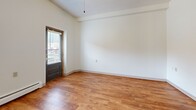 Located at 910 Portland Avenue in Minneapolis, MN, this single-floor unit offers a well-organized layout designed to maximize every square foot. Warm hardwood-style flooring flows consistently throughout the entire space, creating a cohesive and inviting atmosphere.

The open main living area benefits from natural light streaming through multiple windows fitted with blinds, and features a ceiling fan overhead. A striking architectural arch leads from the entry hallway into the living space, adding a distinctive design element. A built-in white vanity with drawers, shelving, and a mirror is thoughtfully integrated into the entryway corridor.

The galley-style kitchen is efficiently arranged with warm wood cabinetry, a stainless steel sink, ample counter space, and a window that brings in additional natural light. White appliances, including a refrigerator and range, complete the kitchen setup. A pass-through counter connects the kitchen to the living area, enhancing the open feel of the space.

The bathroom is clean and functional, featuring a full soaking tub with shower, a wall-mounted sink with mirror, and accessibility grab bars. Baseboard heating is present throughout, ensuring comfort year-round. A textured ceiling is consistent across the unit, adding subtle architectural character to the overall design.