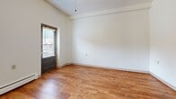 Located at 910 Portland Avenue in Minneapolis, MN, this single-floor unit offers a well-organized layout designed to maximize every square foot. Warm hardwood-style flooring flows consistently throughout the entire space, creating a cohesive and inviting atmosphere.

The open main living area benefits from natural light streaming through multiple windows fitted with blinds, and features a ceiling fan overhead. A striking architectural arch leads from the entry hallway into the living space, adding a distinctive design element. A built-in white vanity with drawers, shelving, and a mirror is thoughtfully integrated into the entryway corridor.

The galley-style kitchen is efficiently arranged with warm wood cabinetry, a stainless steel sink, ample counter space, and a window that brings in additional natural light. White appliances, including a refrigerator and range, complete the kitchen setup. A pass-through counter connects the kitchen to the living area, enhancing the open feel of the space.

The bathroom is clean and functional, featuring a full soaking tub with shower, a wall-mounted sink with mirror, and accessibility grab bars. Baseboard heating is present throughout, ensuring comfort year-round. A textured ceiling is consistent across the unit, adding subtle architectural character to the overall design.