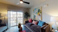 This single-floor residence offers a thoughtfully designed layout that balances modern finishes with a warm, livable atmosphere. The open-concept living area serves as the heart of the home, featuring wood-look flooring, a ceiling fan, and a sliding glass door that opens to a private balcony — flooding the space with natural light and offering outdoor views. The kitchen is a standout feature, showcasing dark espresso cabinetry that extends to the ceiling, stainless steel appliances, a subway tile backsplash, granite countertops, and a peninsula with bar seating illuminated by a stylish pendant light. The kitchen and dining area flow seamlessly together, creating an ideal space for both everyday living and entertaining. The bedroom is a comfortable retreat, finished with plush carpeting, a window with ample natural light, and a tray ceiling detail that adds architectural character. The en-suite bathroom is well-appointed with granite countertops, dark wood vanity cabinetry, a walk-in shower, and direct access to a spacious walk-in closet complete with built-in shelving and hanging storage. Throughout the residence, neutral tones and clean lines create a cohesive and inviting ambiance.