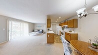 Located at 1700 Bayview Dr in Fort Wayne, Indiana, this one-bedroom, one-bathroom residence offers a thoughtfully designed single-floor layout. The open-concept living area is anchored by plush wall-to-wall carpeting and features large sliding glass doors dressed with vertical blinds, allowing abundant natural light and providing direct access to an outdoor patio with exterior views. The living room offers comfortable space for relaxing and entertaining, flowing seamlessly into the dining area, which is highlighted by a chandelier overhead and a round mirror accent on the wall. The kitchen is well-equipped with warm oak cabinetry, ample upper and lower storage, white appliances including a refrigerator and electric range, a built-in dishwasher, and durable tile flooring. A pantry closet provides additional storage convenience. The bedroom is a quiet retreat featuring soft carpet, natural light from a window with elegant drapery, and two closets offering generous storage. The full bathroom includes a tub-shower combination with tile surround and tile flooring. An in-unit laundry area with washer and dryer hookups adds everyday practicality, completing this well-appointed and efficiently designed residence.