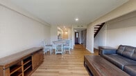 Located at 1943 Cambridge Dr in Kent, Ohio, this two-story home offers a well-designed layout spread evenly across two floors. The main level features an open-concept living, dining, and kitchen area united by warm light wood flooring throughout. The living room is bright and inviting, highlighted by a sliding glass door that fills the space with natural light and provides direct access to the outdoor yard. The kitchen is well-appointed with white shaker cabinetry, granite countertops, stainless steel appliances, and a louvered pantry door, flowing seamlessly into the dining area with ample room for a full dining set. A striking open-tread staircase with a wood handrail and clean white balusters serves as an architectural focal point connecting the two floors. Upstairs, the spacious primary bedroom offers generous proportions with hardwood-style flooring, exposed brick accent walls, and baseboard heating. The second bedroom features a large window with outdoor views and an open closet with built-in rod. The full bathroom is finished with a granite-topped white vanity, a tub-shower combination, and light wood flooring, completing this clean and move-in-ready home.