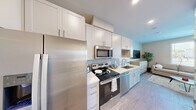 Located at 1639 E Tropicana Ave in Las Vegas, NV, this thoughtfully designed one-bedroom, one-bathroom unit offers a smart and functional layout with modern finishes throughout. The open-concept living area seamlessly connects to a well-appointed galley-style kitchen, which features white shaker cabinetry extending to the ceiling, a light gray subway tile backsplash, quartz countertops, and a full suite of stainless steel appliances including a refrigerator, electric range, microwave, and dishwasher. Wood-look plank flooring runs throughout the unit, adding warmth and continuity across the space. The bedroom area is generously proportioned relative to the overall footprint, accommodating a bed, seating, and storage, and is brightened by a window with natural light and fitted with a ceiling fan. A dedicated closet provides organized storage. The bathroom is clean and contemporary, featuring a white vanity with an undermount sink, a large mirror, and wood-look tile flooring. Neutral warm-toned walls throughout create a calm, cohesive ambiance. A full-length mirror in the living area enhances the sense of openness, making this compact unit feel bright and inviting.