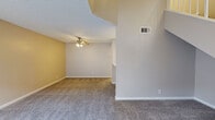 This two-story home offers a practical and well-organized layout across two floors, providing comfortable living for a variety of lifestyles. The main floor features an open-concept kitchen and living area, where a pass-through counter connects the kitchen to the carpeted living space, creating an easy flow for everyday living and entertaining. The kitchen is equipped with white cabinetry, stainless steel appliances including a refrigerator and range, and overhead lighting. Plank-style flooring runs through the kitchen and dining area, while plush carpet covers the living room.

Upstairs, three bedrooms offer ample personal space, including a generously sized primary bedroom with mirrored sliding closet doors and access to a walk-in closet. A stacked washer and dryer unit is conveniently located within the upper floor. Both bathrooms feature clean white vanities with brushed gold hardware, a white toilet, and wood-look plank flooring, maintaining a consistent, light aesthetic throughout. Additional walk-in and standard closets provide substantial storage. Textured ceilings are present throughout, and ceiling fans contribute to comfortable airflow. The bedrooms are brightened by windows with blinds, allowing natural light to fill each room.