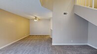 This two-story home offers a practical and well-organized layout across two floors, providing comfortable living for a variety of lifestyles. The main floor features an open-concept kitchen and living area, where a pass-through counter connects the kitchen to the carpeted living space, creating an easy flow for everyday living and entertaining. The kitchen is equipped with white cabinetry, stainless steel appliances including a refrigerator and range, and overhead lighting. Plank-style flooring runs through the kitchen and dining area, while plush carpet covers the living room.

Upstairs, three bedrooms offer ample personal space, including a generously sized primary bedroom with mirrored sliding closet doors and access to a walk-in closet. A stacked washer and dryer unit is conveniently located within the upper floor. Both bathrooms feature clean white vanities with brushed gold hardware, a white toilet, and wood-look plank flooring, maintaining a consistent, light aesthetic throughout. Additional walk-in and standard closets provide substantial storage. Textured ceilings are present throughout, and ceiling fans contribute to comfortable airflow. The bedrooms are brightened by windows with blinds, allowing natural light to fill each room.