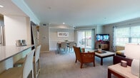 This single-floor residence offers a thoughtfully designed layout that balances comfort and functionality across several well-defined spaces. A hardwood-floored entryway transitions into carpeted living areas, establishing a warm and welcoming tone throughout.

The living room is generously proportioned, featuring crown molding, recessed lighting, and large windows that invite abundant natural light. A sliding glass door opens directly onto a private balcony, extending the living space outdoors. Adjacent to the living room, the dining area accommodates a full dining table and is accented by a framed art piece above a chair rail, with direct balcony access as well.

The kitchen is equipped with stainless steel appliances, including a range with an over-the-range microwave, white cabinetry with matte black hardware, subway tile backsplash, and grey countertops, offering a clean, modern aesthetic.

The primary bedroom includes a walk-in closet with built-in shelving, while a second bedroom features a window with natural light and plush carpeting. The full bathroom is finished with large-format beige tile surrounding a soaking tub and shower combination, complemented by wood-look flooring and glass enclosure.