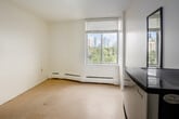 Located at 280 Dundas St E in Toronto's vibrant downtown east corridor, this compact unit offers an efficient and functional layout across a single floor. The space consists of a welcoming hallway and a dedicated bedroom, designed to make the most of every square foot.

The hallway serves as a practical entry point, featuring a built-in closet for storage and a wall-mounted light fixture that adds a warm touch. A pass-through window opening connects to a compact kitchen area, enhancing the sense of openness between spaces. Light-toned flooring runs throughout, contributing to a clean, cohesive aesthetic.

The bedroom is the highlight of the unit, benefiting from a large window that frames lush treetop views with the Toronto city skyline visible in the background. Natural light fills the room generously, creating a bright and airy atmosphere. A baseboard heating unit runs beneath the window, ensuring year-round comfort. The white walls throughout keep the space feeling fresh and open.

A full-length mirror near the entry adds depth and functionality. The overall design is minimal and neutral, offering a blank canvas well-suited for personalization. Situated on the 9th floor, this unit provides an elevated urban perspective in one of Toronto's most accessible and dynamic neighbourhoods.