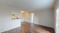 This single-floor residence offers a well-organized layout with distinct living, sleeping, and functional zones. The living area is finished with rich, dark hardwood-style flooring that extends throughout the main space, complemented by neutral white walls and crown molding. Natural light enters through a set of French doors fitted with white plantation shutters, creating a bright and open atmosphere. A peninsula counter separates the living area from the galley-style kitchen, which features warm wood cabinetry, granite-look countertops, and white appliances including a range, dishwasher, and refrigerator. The kitchen is efficiently designed with ample cabinet storage on both sides.

The bedroom is generously sized, finished with plush wall-to-wall carpeting, a ceiling fan with integrated lighting, and a window with blinds for natural light. The room provides direct access to a walk-in closet outfitted with a wire shelving system, as well as an en-suite bathroom featuring a full soaking tub surrounded by clean white tile. Consistent neutral tones, functional layouts, and practical finishes give the space a comfortable and move-in ready character.
